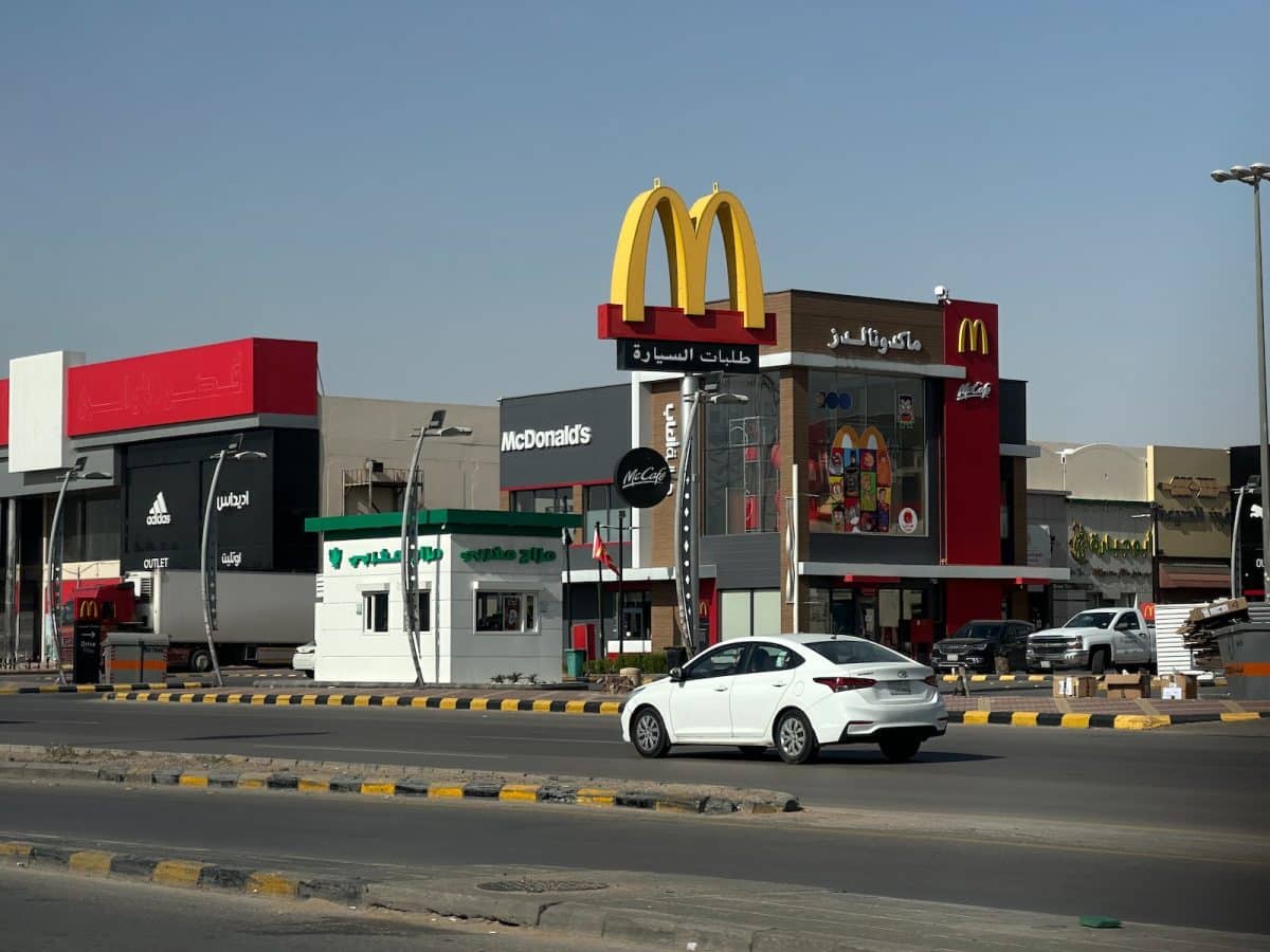 a white car driving down a street next to a mcdonald's